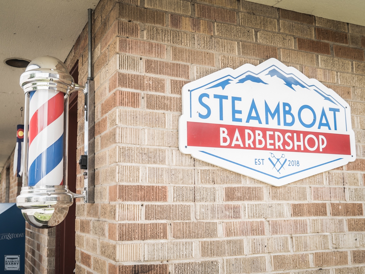 Barber pole and Steamboat Barbershop sign outside of the shop.
