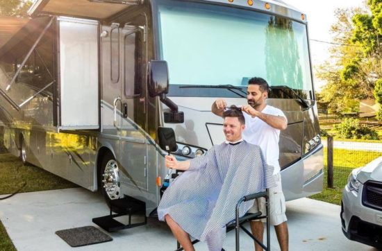 John cutting hair outside in front of their RV.