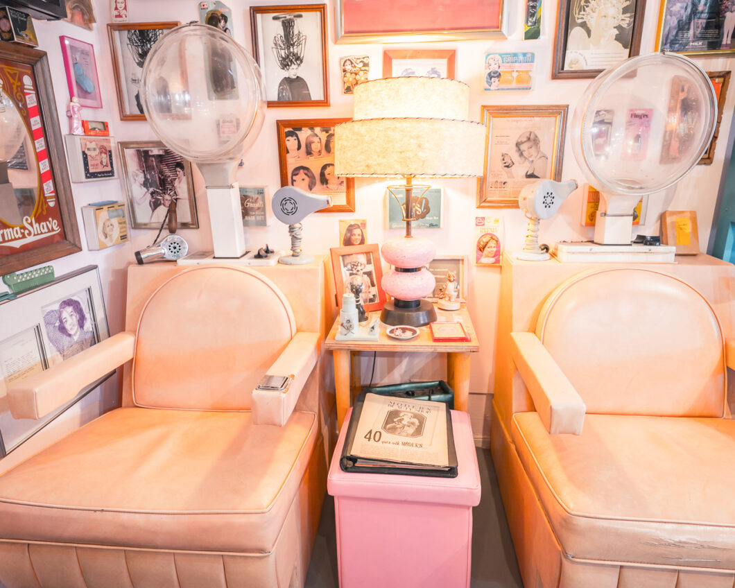 Vintage pastel colored beauty salon chairs against a wall of framed photos at the Beauty Bubble Salon